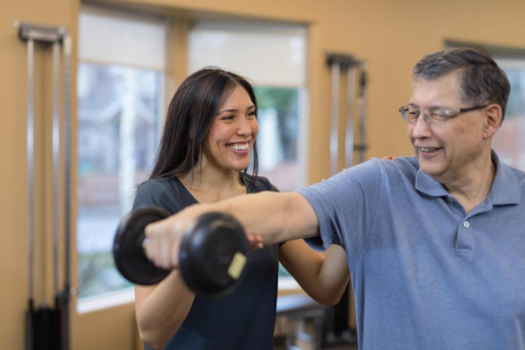 Physical therapist assisting a man with a dumbbell
