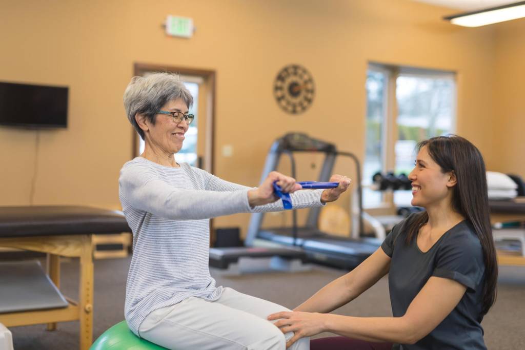 Physical therapist assisting a woman with a resistance band